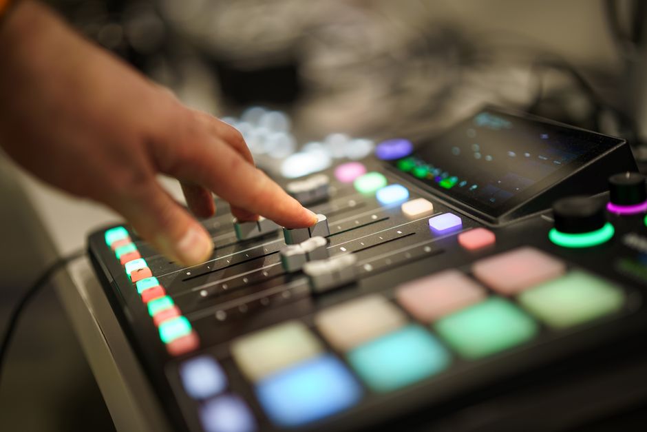 A hand adjusting faders on a professional audio mixer